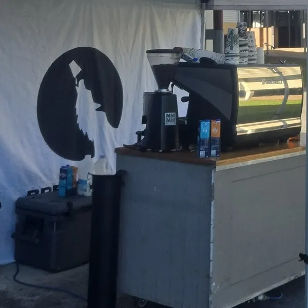 The Brew Moon Cafe coffee cart and espresso machine under a white gazebo, the moon and wolf on the wall behind