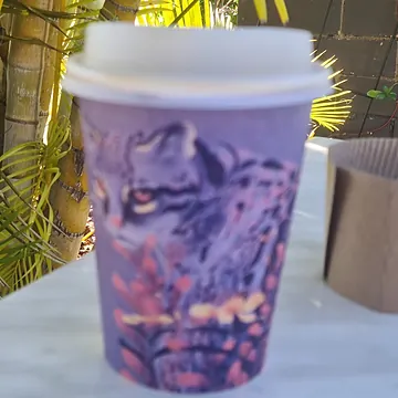 A takeaway coffee in a printed paper cup on a marble table at Brew Moon Cafe