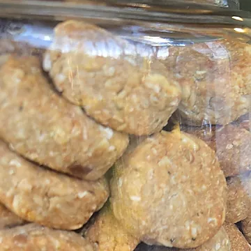 A glass jar full of dog treats on the counter at the window